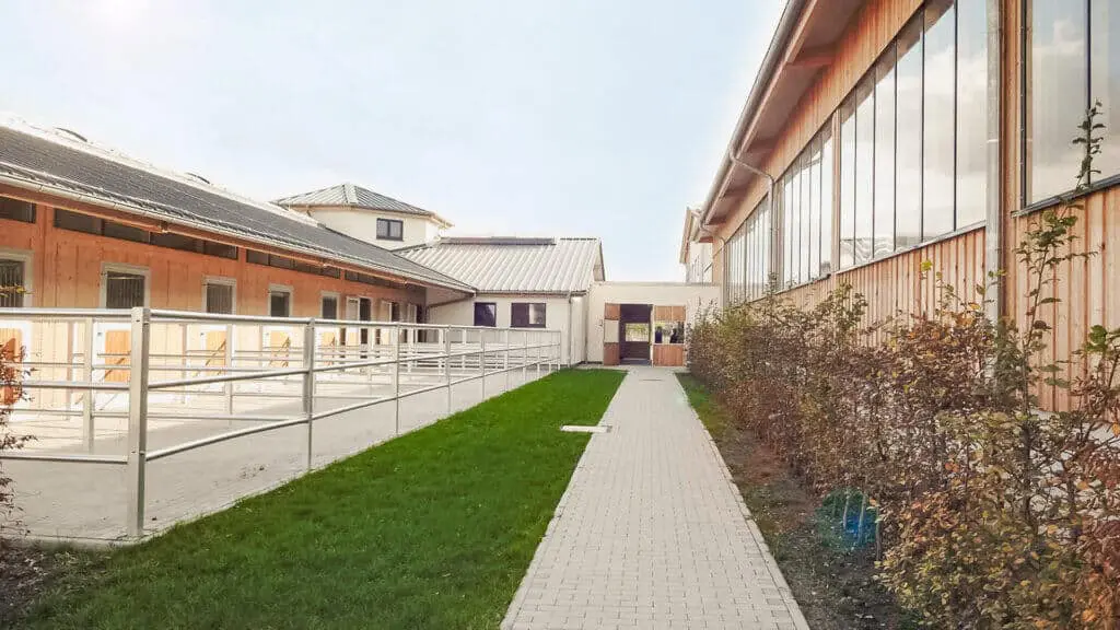 Weg auf der Reitanlage zwischen Paddocks und Reithalle