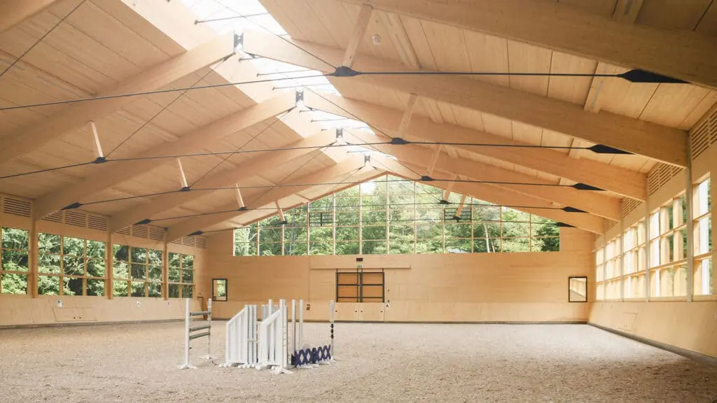 Lichtdurchflutete Reithalle mit Hindernissen auf der Reitflaeche