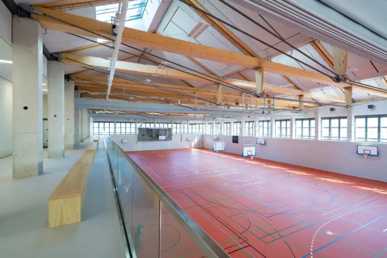 Sporthalle in Holzbauweise, erste 8-Fach Sporthalle Europas von Schlosser planprojekt und SCHLOSSER Holzbau. Hier zu sehen, die andere Halle im gleichen Gebäude mit rotem Sporthallenboden quer.
