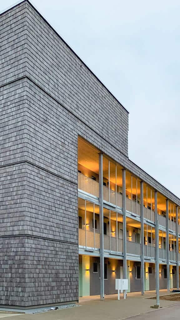Wohngebäude von aussen mit Schindelfassade in der Daemmerung