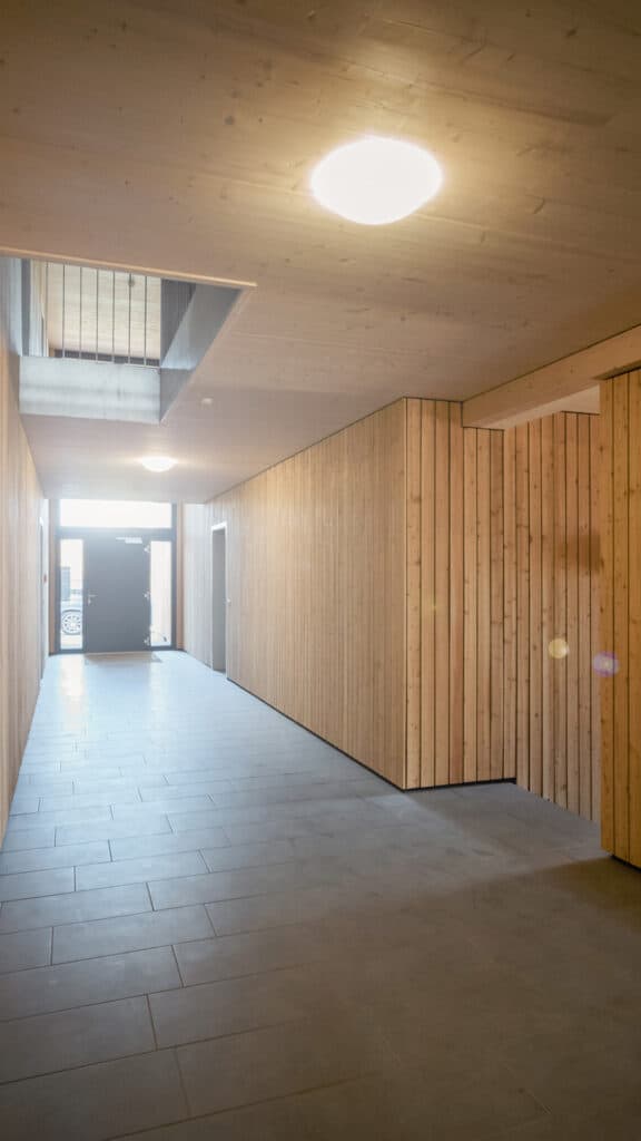Flur eines Mehrfamilienhauses mit Holzdecke und Holzverkleidung an den Waenden