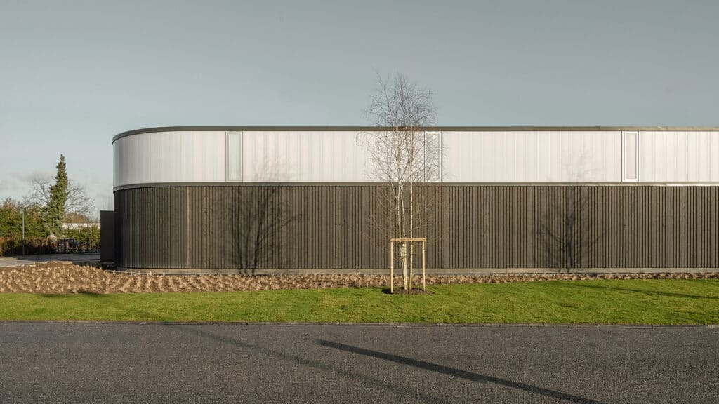 Blick von aussen auf modernes Gebaeude mit dunkler Holzfassade