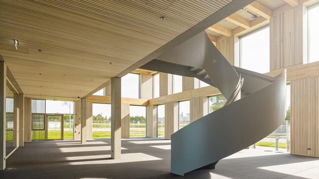 Heller Eingangsbereich eines Unternehmens in Holzbauweise mit Stahltreppe im Vordergrund