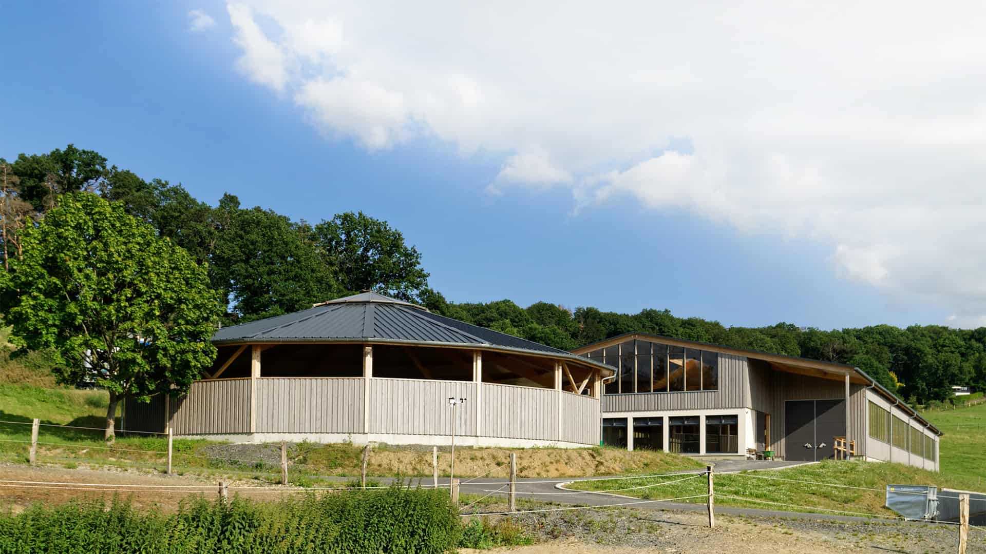 Reitanlage mit Reithalle und Longierhalle mit grau gestrichener Holzfassade