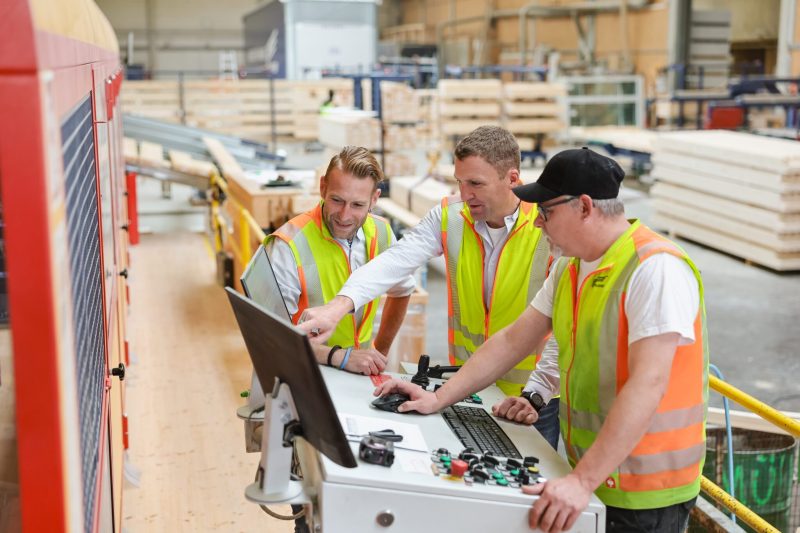 Mitarbeiter von Schlosser Holzbau besprechen an der Abbund Maschine